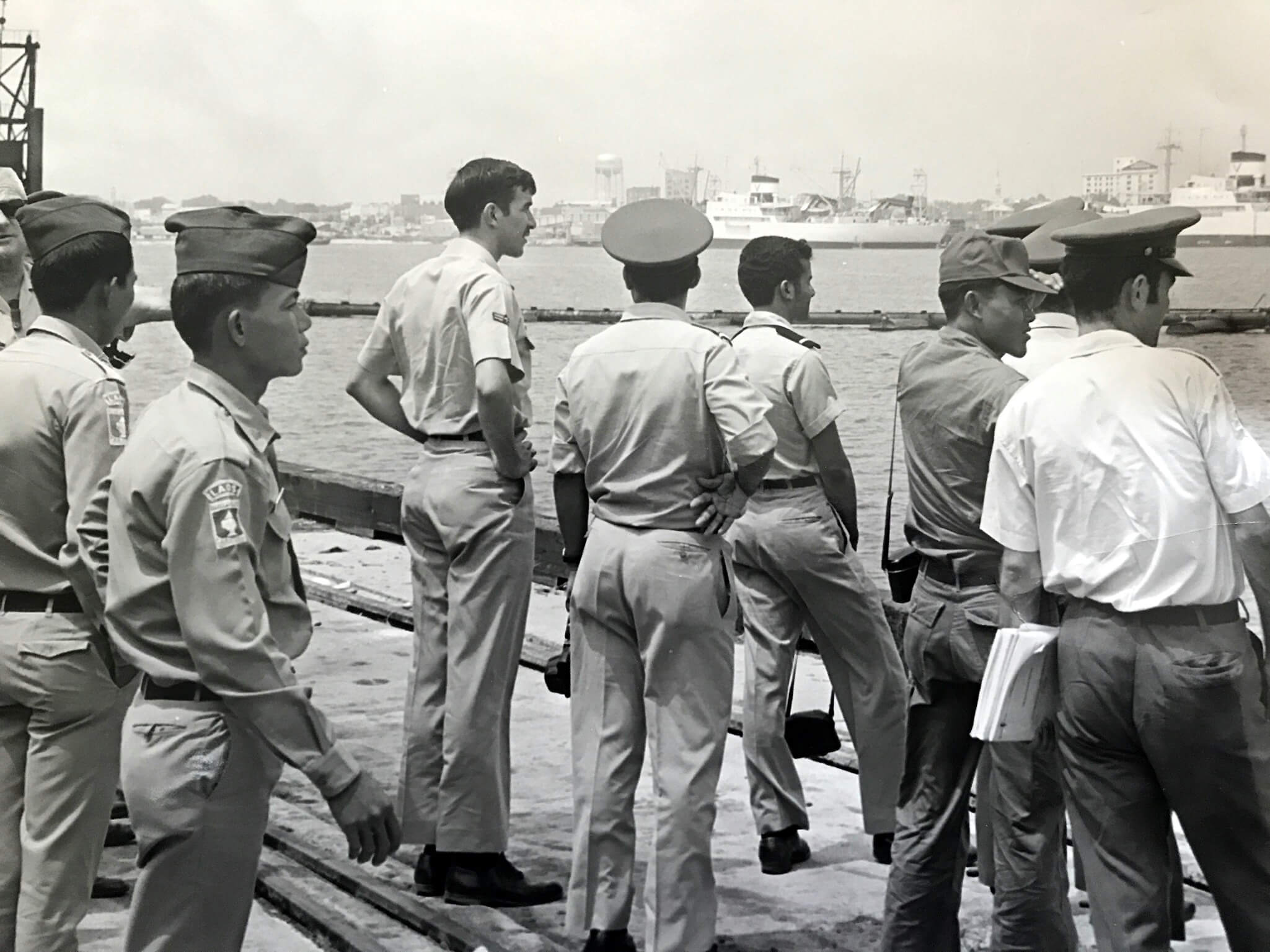 Group of Air Force soldiers standing on a ship or dock, looking out over the water.