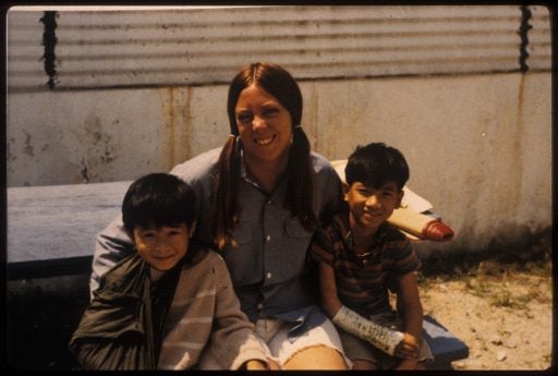 Returning from a day at China Beach. Marcia sitting between two young Vietnamese children, everyone is smiling.