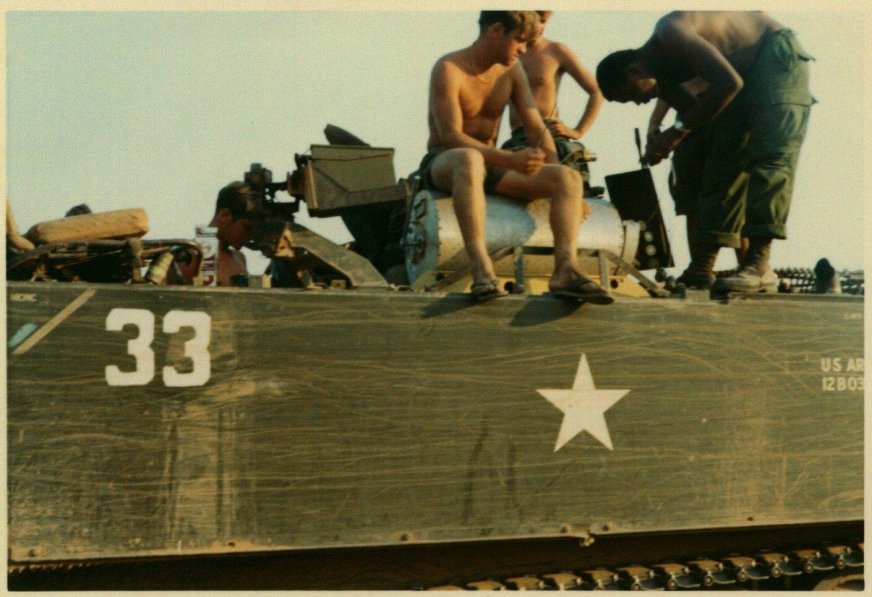 U.S. soldiers hanging out on top of a tank.