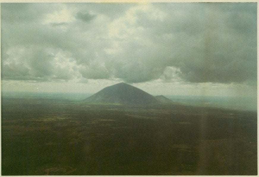A photo of a mountain rising out of plains; possibly Nui Ba Den a.k.a. Black Virgin Mountain.