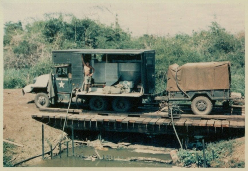 A military motor vehicle crossing over a small bridge.