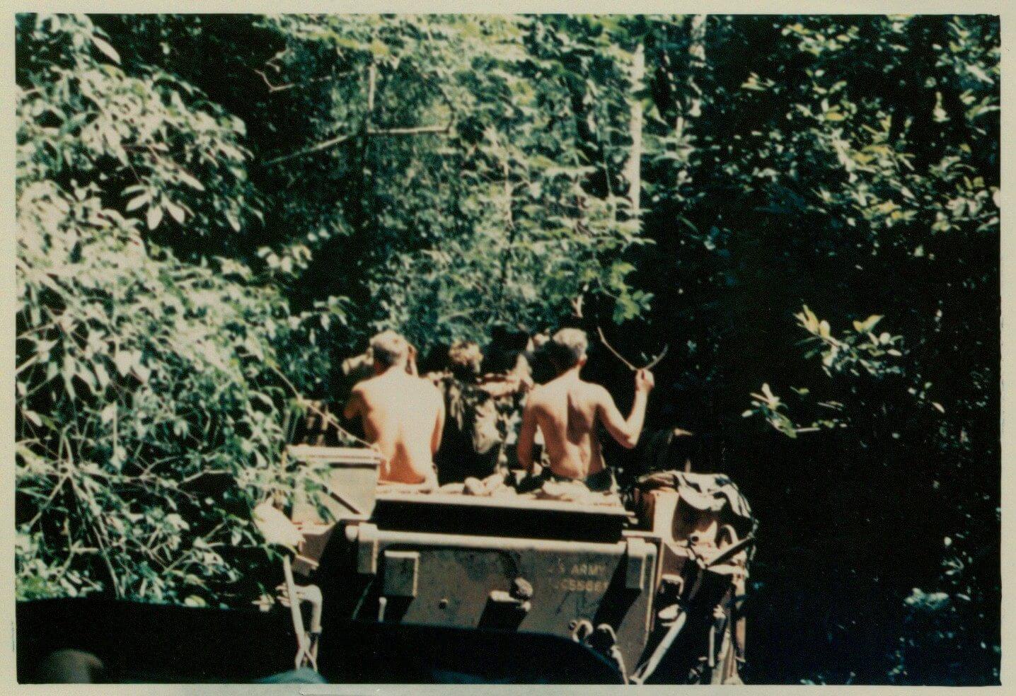 A military vehicle from the rear, driving into the jungle.