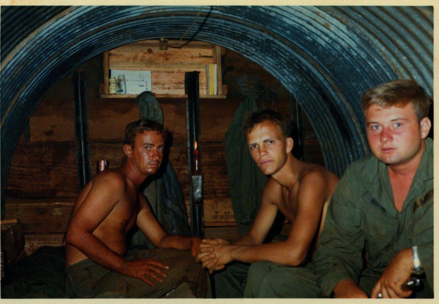 Three soldiers sitting inside a bunker, looking serious.
