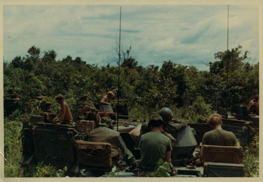 Soldiers in military motor vehicles, riding into the jungle.