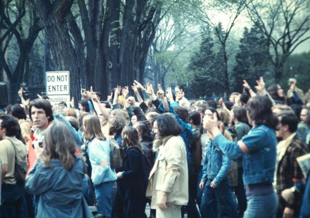 A crowd of student protesters, many holding up peace signs.