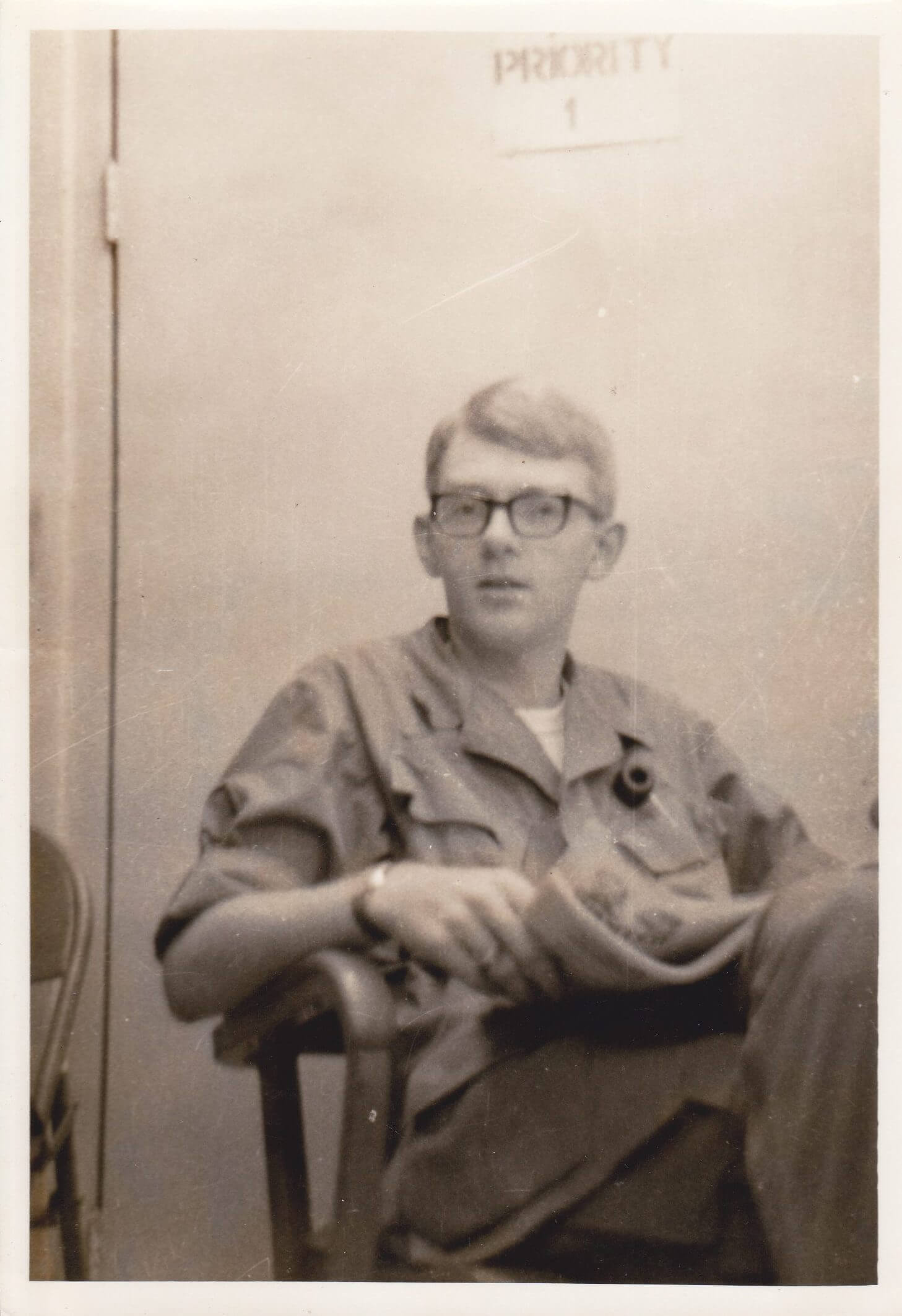 Young soldier with glasses, sitting and reading a newspaper.