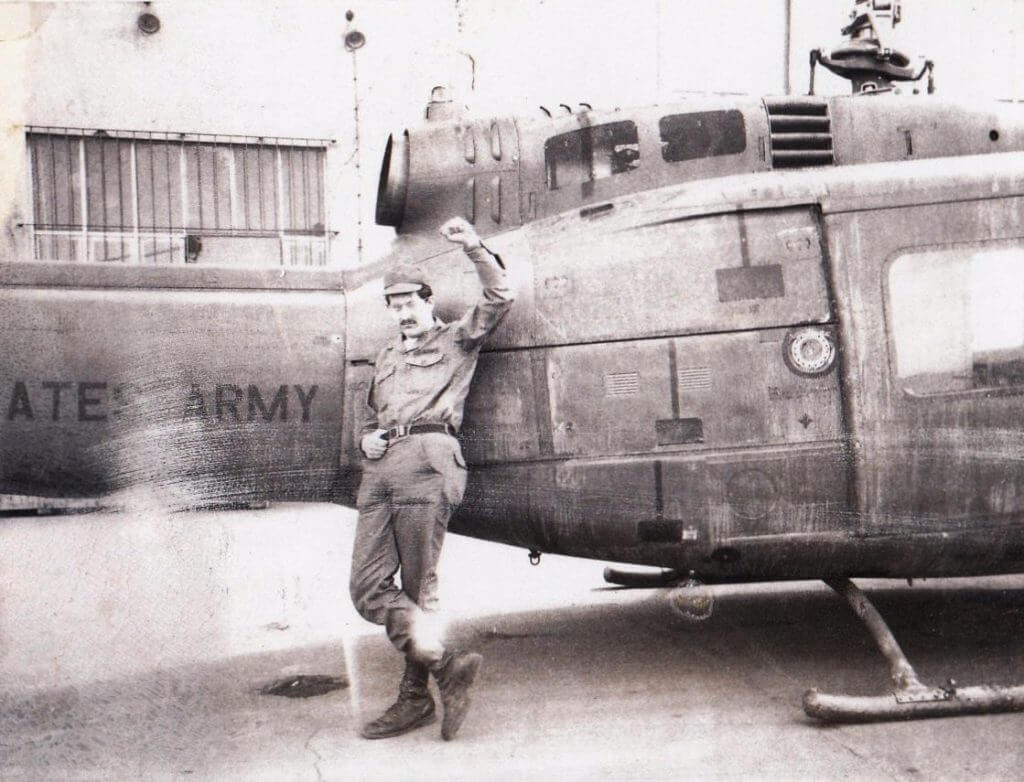 Soldier holding up his fist, leaning against a U.S. helicopter.