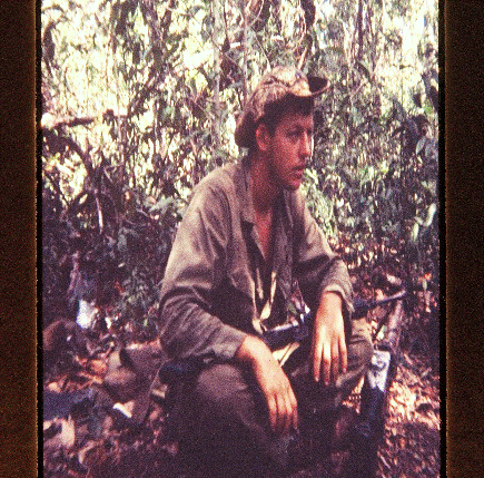 Young man seated in a jungle.