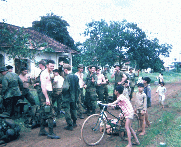 A group of U.S. soldiers and young Asian children with bicycles.