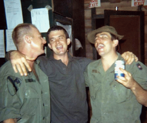 Three young soldiers, laughing and drinking beer.