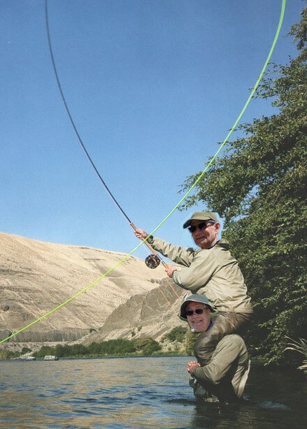 Photoshopped image of two men fly fishing, one sitting on the other's shoulders.