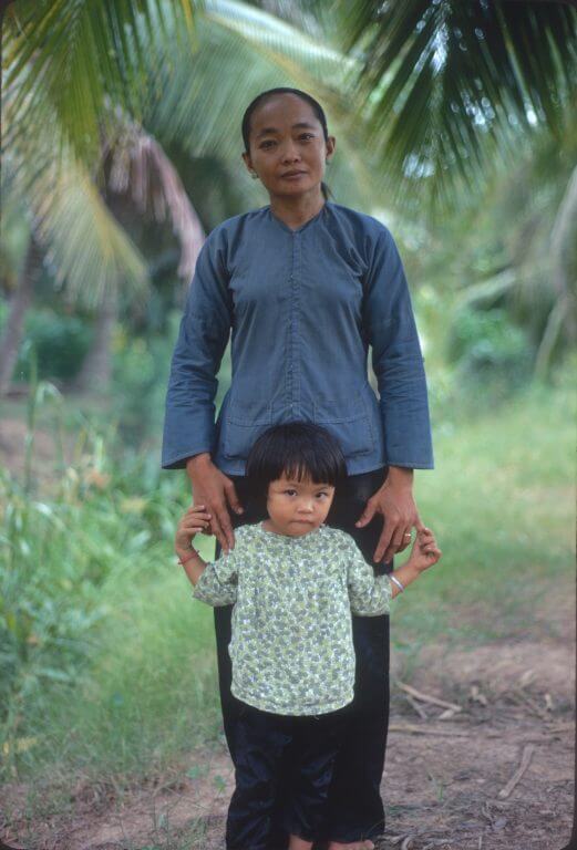 Asian woman with young child, standing in the jungle.