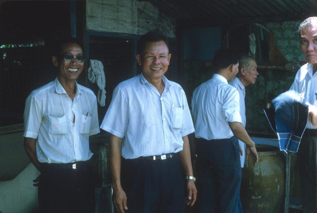 Photo of three Asian men, smiling for the camera.