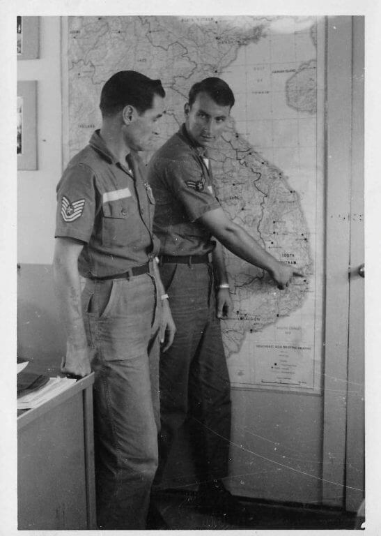 Young soldier pointing out a location on a map of Vietnam to older soldier.