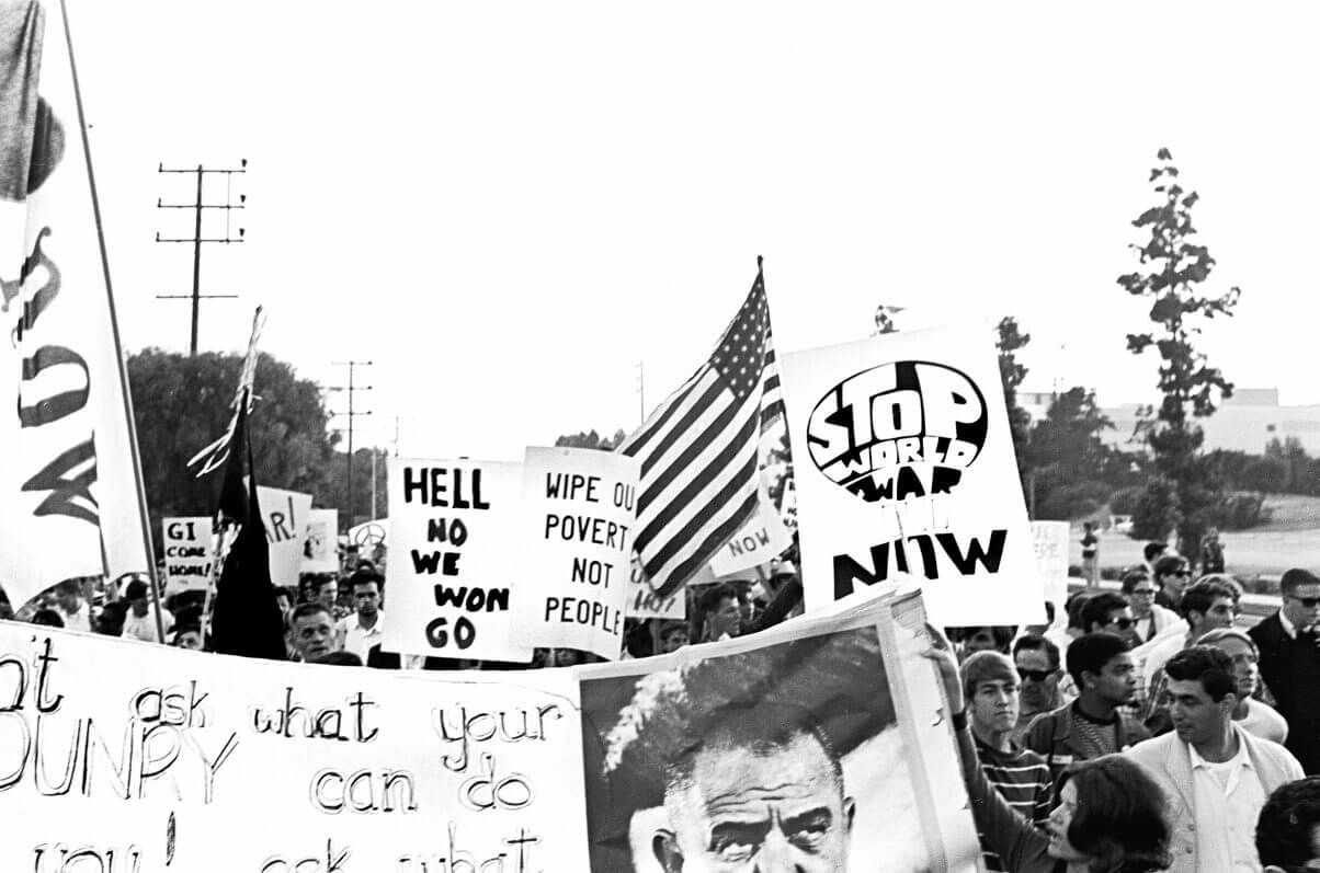 Protesters with signs and an an American flag.