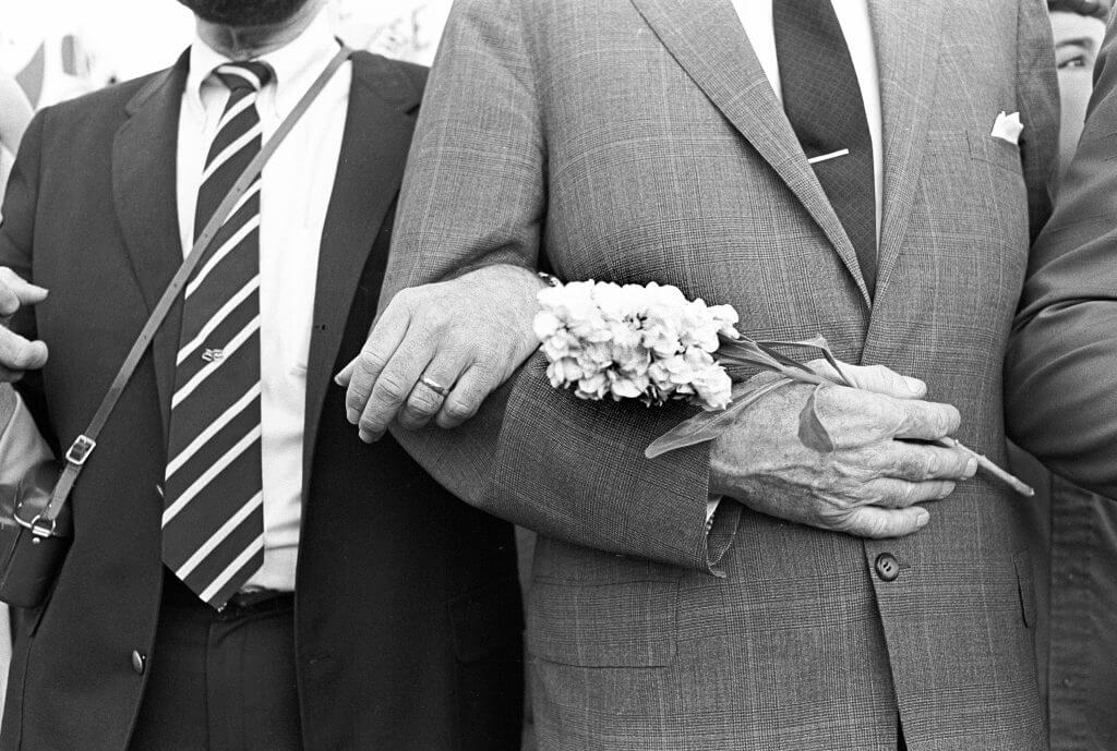 Close-up shot of men in suits' arms, linked in protest and solidarity.