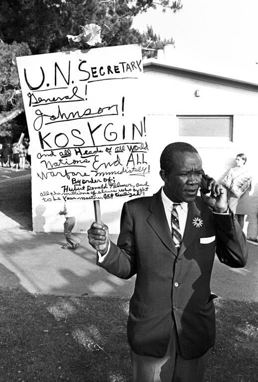 African American male holding sign that reads: "U.N. Secretary General! Johnson! Kosygin! and all heads of the world nations. End all warfare immediately. By order of: Hubert Donald Palmer and all the millions of slaves who ought to be your masters. Art civilized."