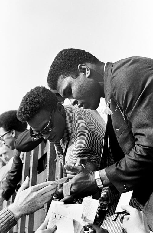 Muhammad Ali signing autographs.