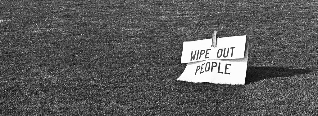 Protest sign propped up on a lawn, reading "Wipe Out People."