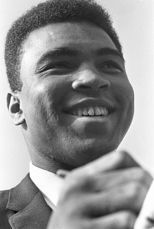 Muhammad Ali smiling and signing an autograph.