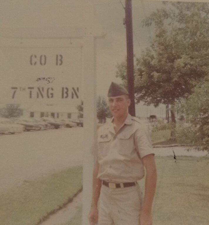 Young soldier standing by a sign outside boot camp.