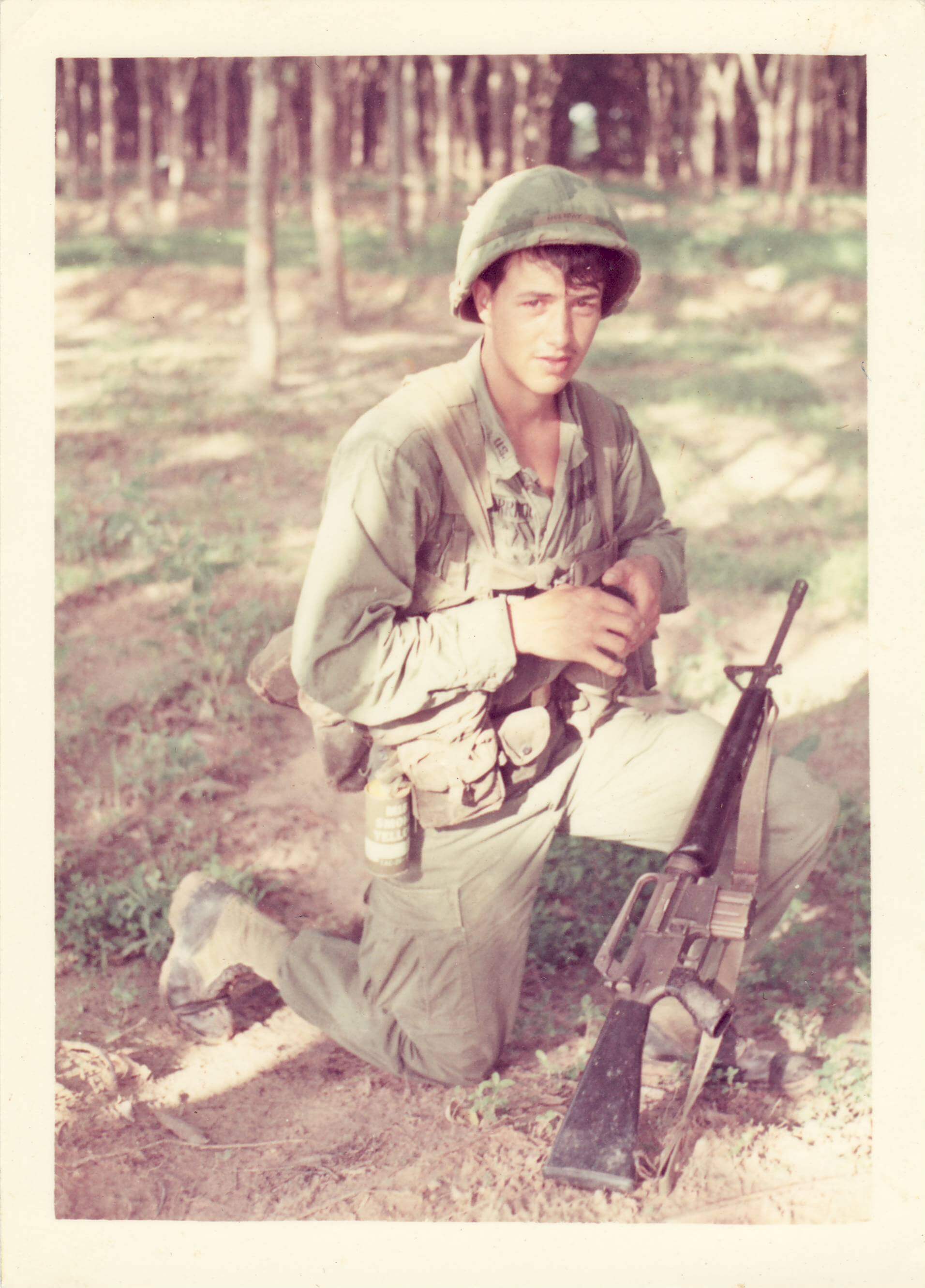 A young soldier kneels with his rifle.