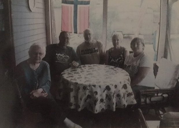 Family photo on a porch, Norwegian flag hanging in the background.