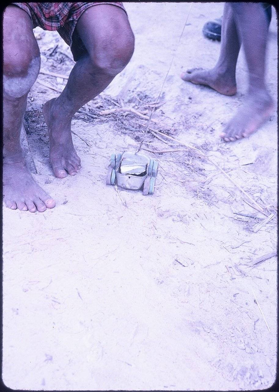 Vietnamese children's toes and toy on a dirt floor.