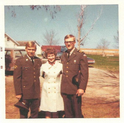 Two young soldiers posing outside with their mother.