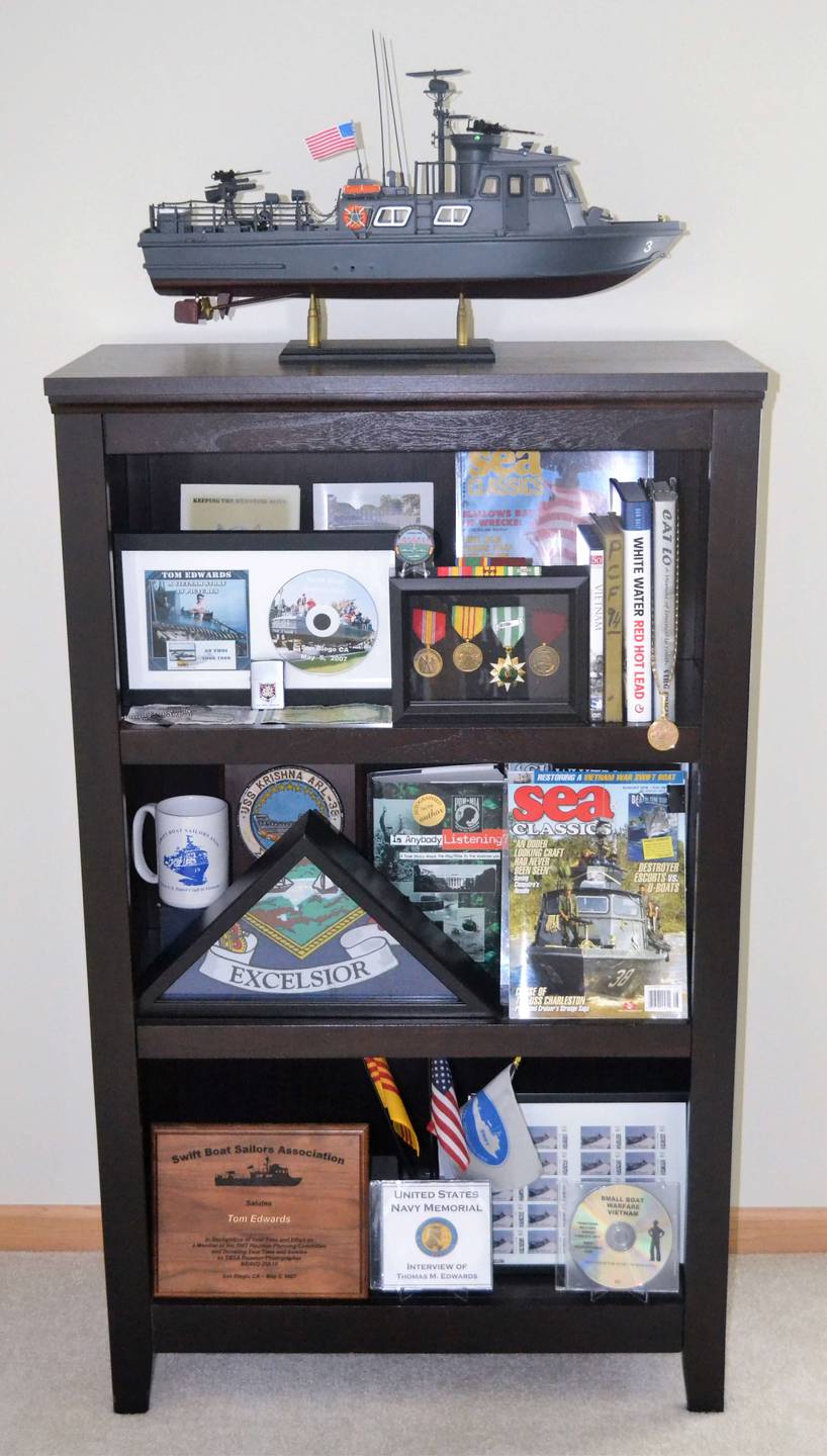A cabinet full of awards and memorabilia, model scale swift boat perched atop.