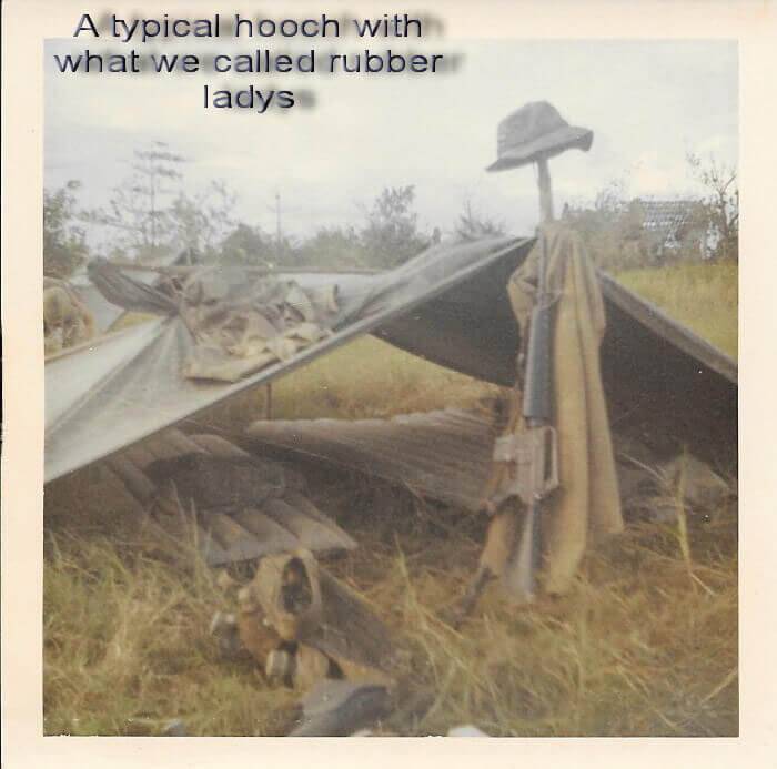 An encampment made in the grass. Text reads: "A typical hooch with what we called rubber ladys."