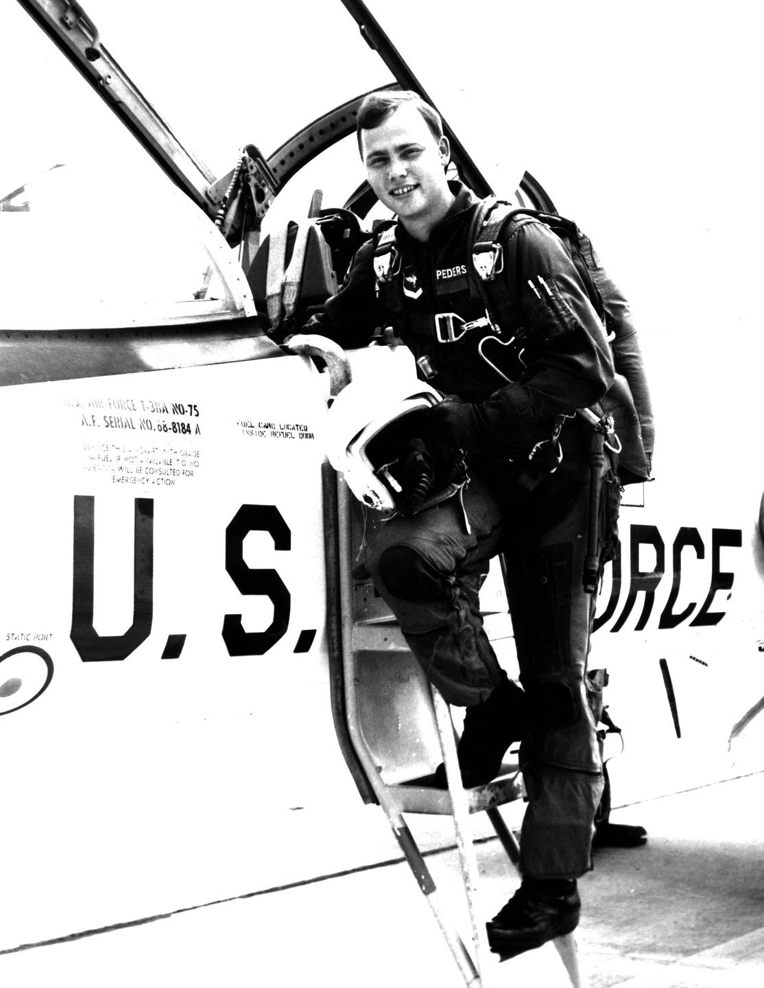 A young pilot standing on the steps to the cockpit.
