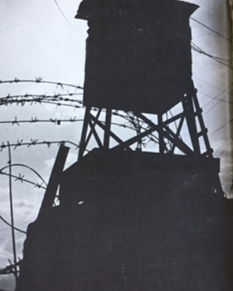 Silhouette of guard tower and razor wire.