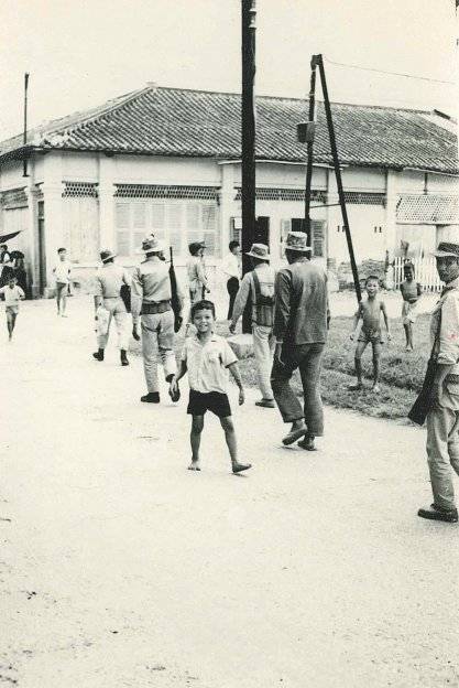 Asian soldiers and children walking in the street; children are coming toward the camera.