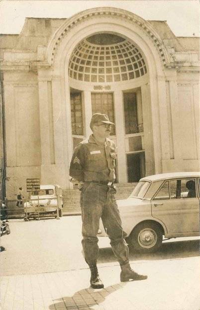 U.S. soldier standing outside what looks to be a Vietnamese governmental building.