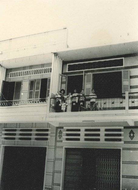 An Asian family on a balcony, smiling down at the photographer.