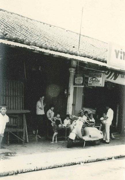 Asian villagers seated outside a restaurant or shop.