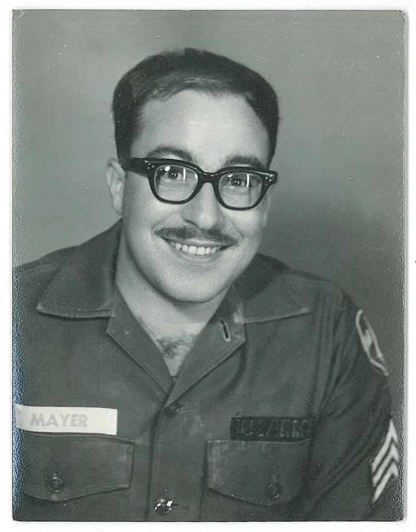 A portrait of a U.S. soldier named Mayer. He wears a mustache and glasses.