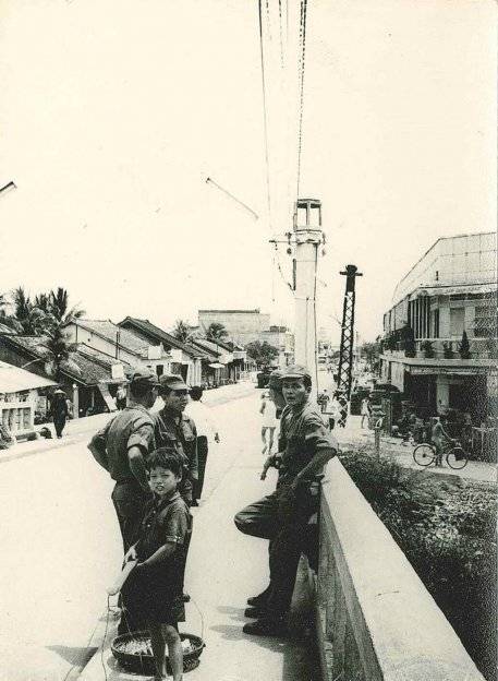Asian soldiers and a young boy on the streets of a Vietnamese city.