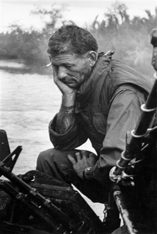 An older U.S. soldier looking sad and reflective, sitting on a boat.