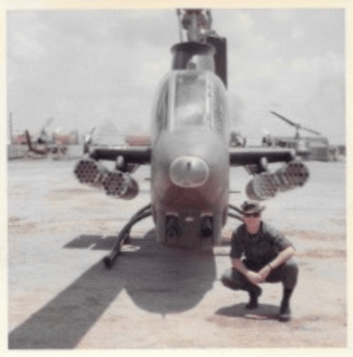 Young soldier crouching next to a military aircraft.