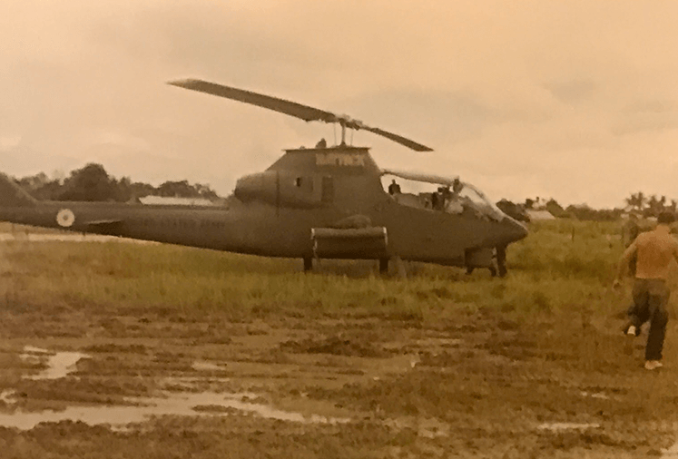 A helicopter in a muddy clearing.