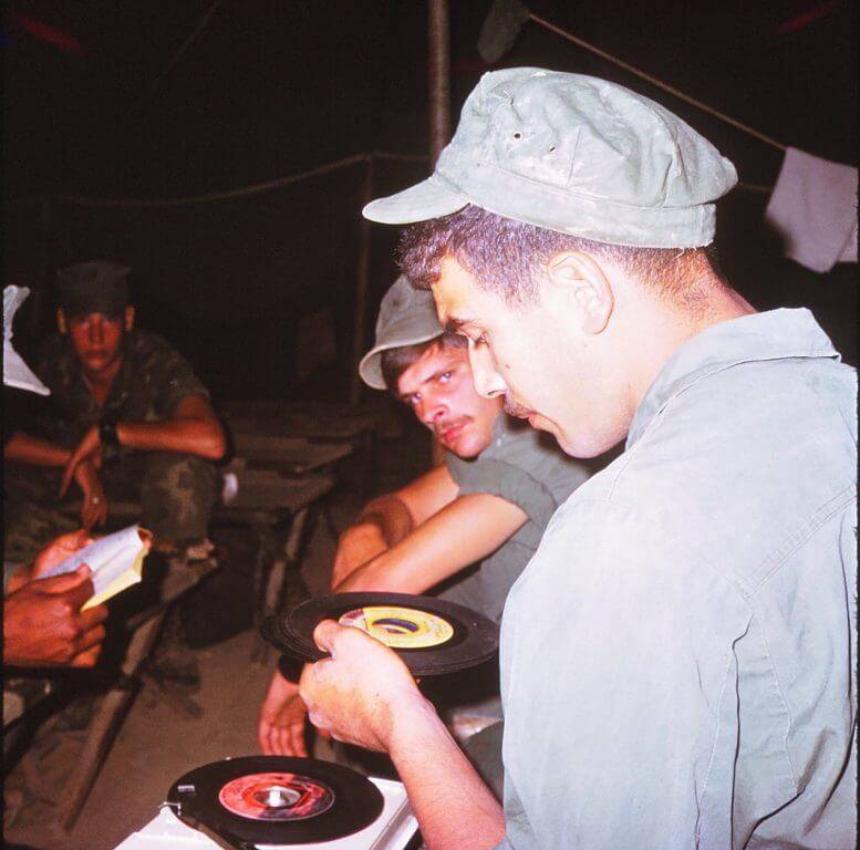 Young soldiers looking at vinyl records.