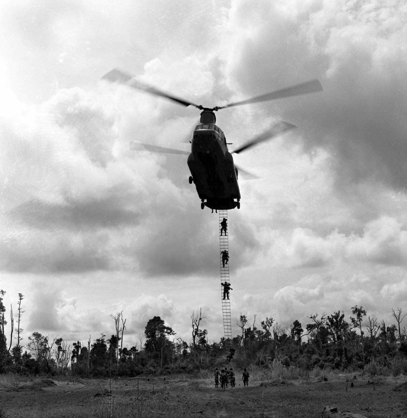 Chinook helicopter picking up soldiers on a ladder.
