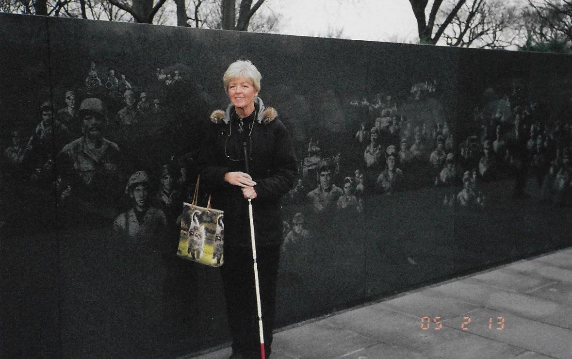 Older woman with cane, standing by the Vietnam War Memorial.