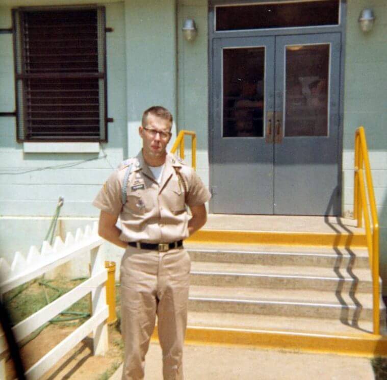 Young soldier in khaki uniform standing outside a building.