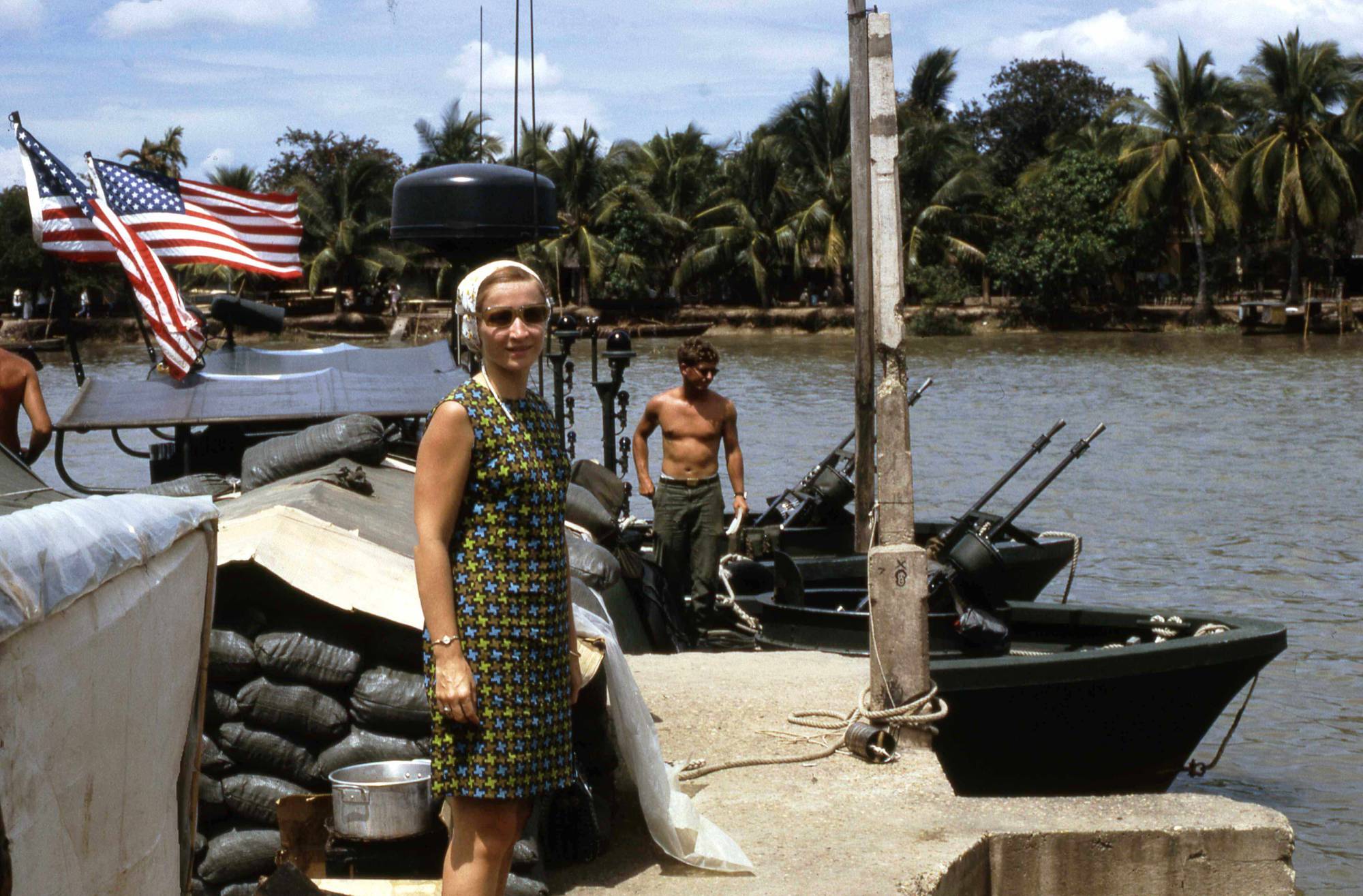 Young woman posing for a photo on a River Patrol Boat with American flags flying