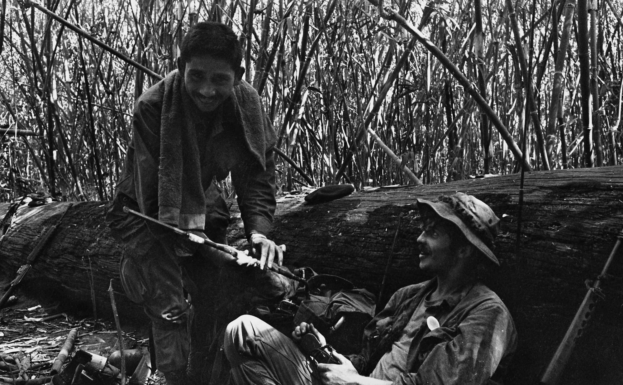 Two soldiers relaxing next to a log.