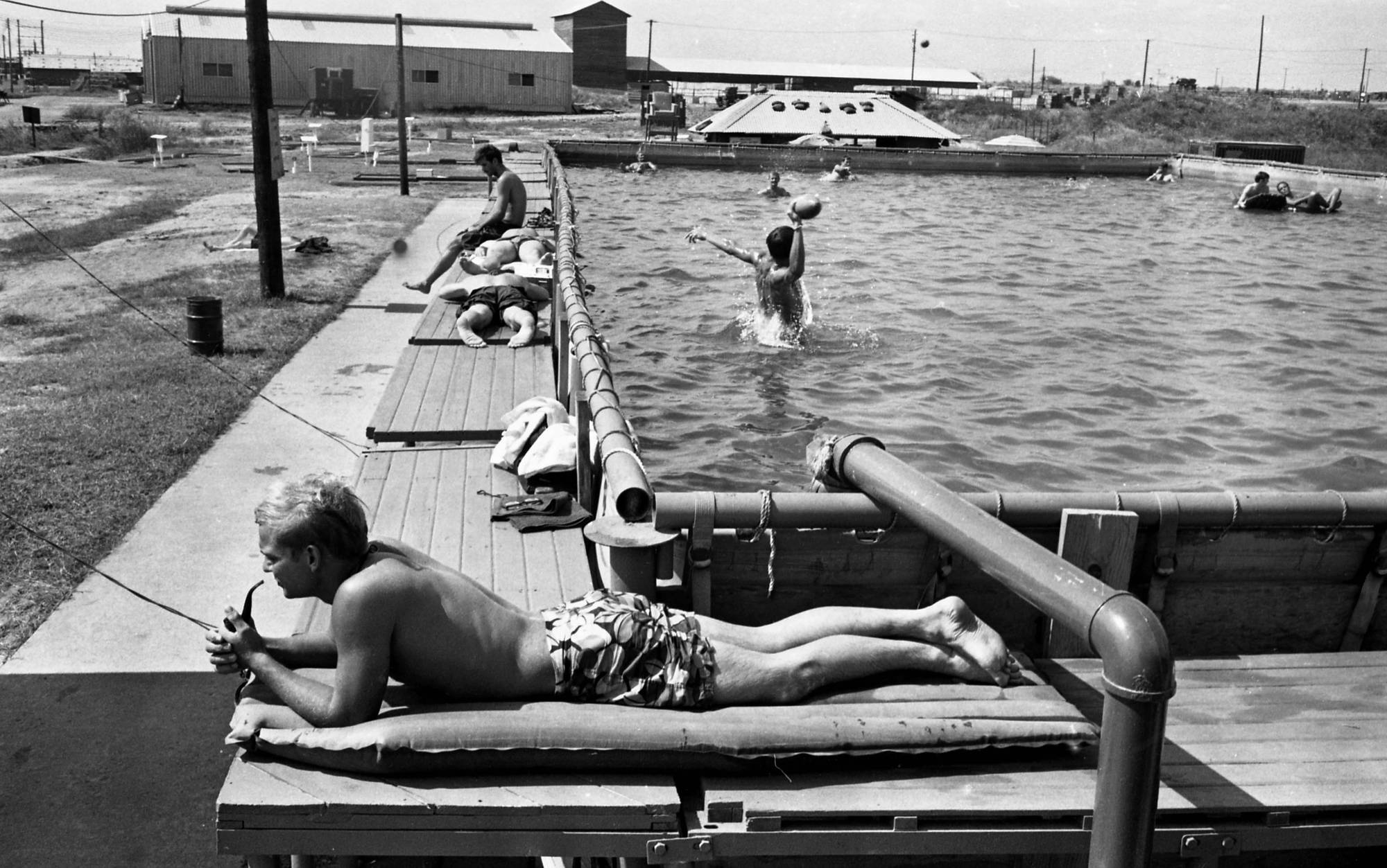 Soldiers sunbathing and swimming at a pool.