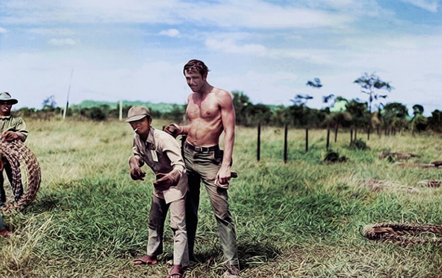 A shirtless U.S. soldier with an Asian soldier, standing in a field.